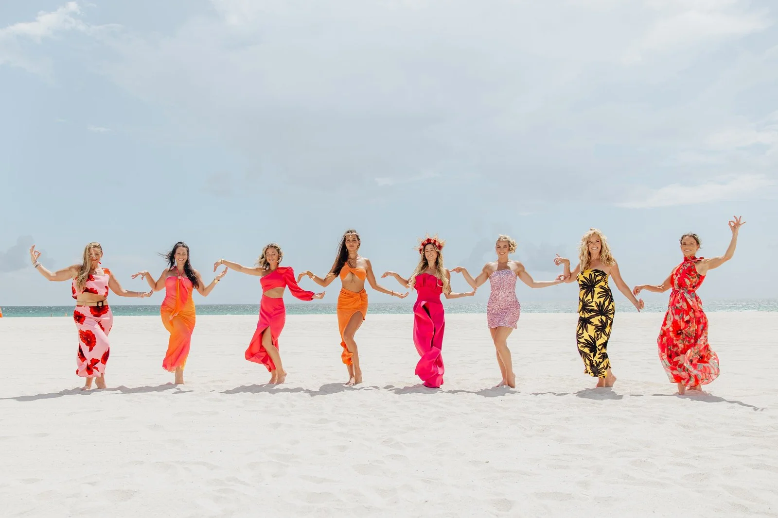 The Summit women in a line on the sand, arms raised