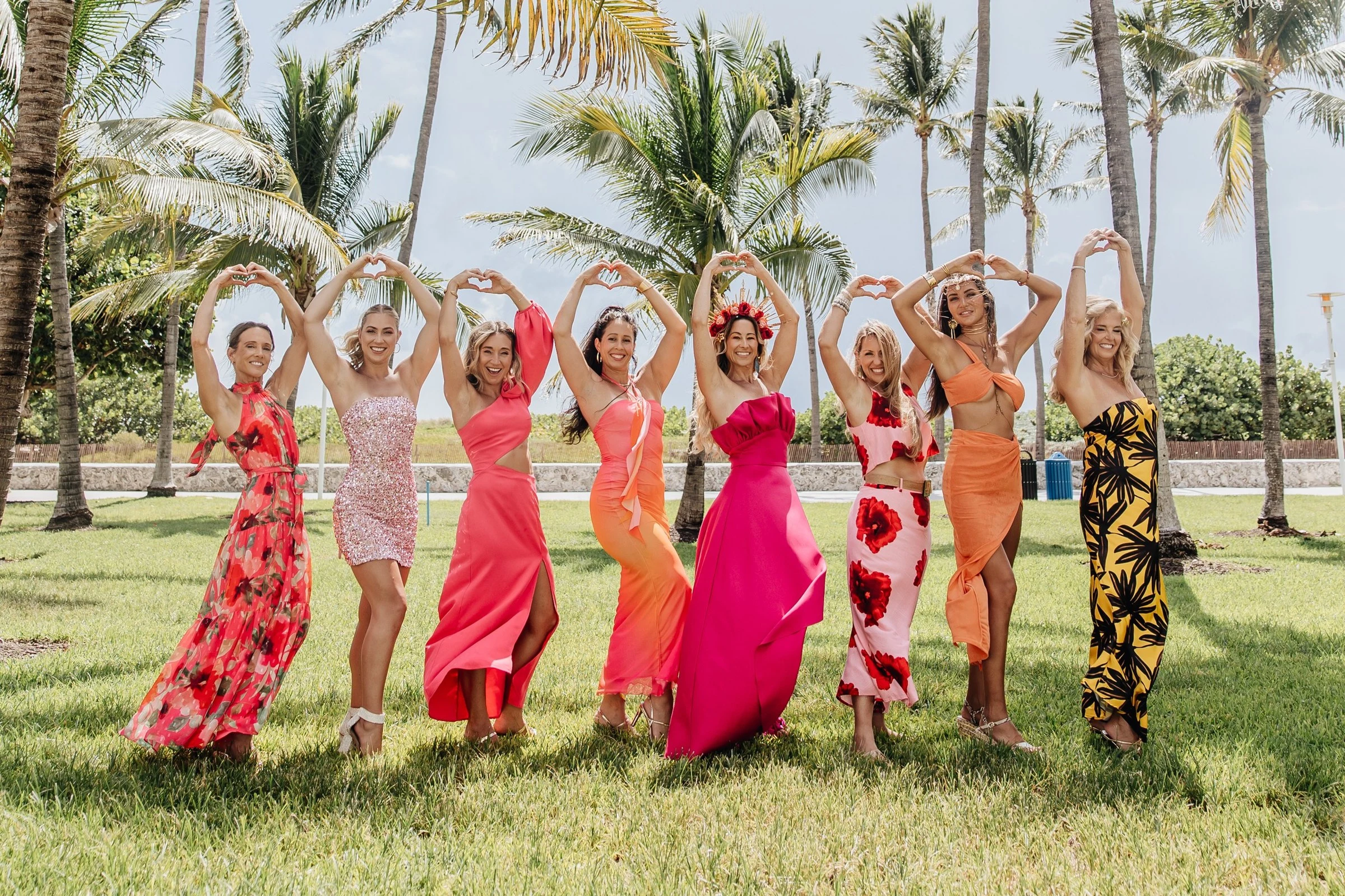 The women of the Starseed Summit on the grass in South Beach, arms raised in hearts above their heads