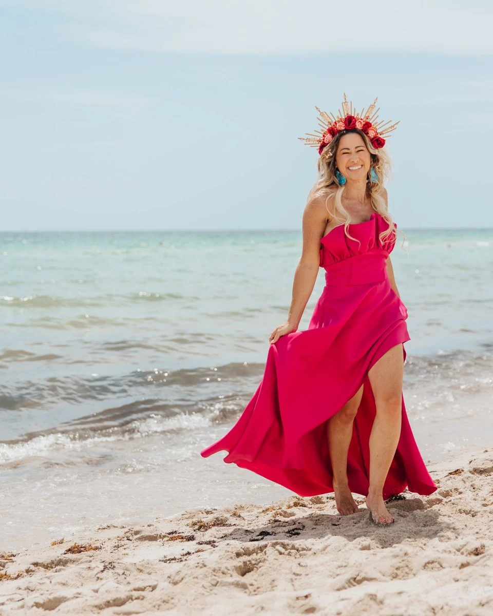 Vanessa Lambert in a hot pink gown and flower crown, full length on the beach